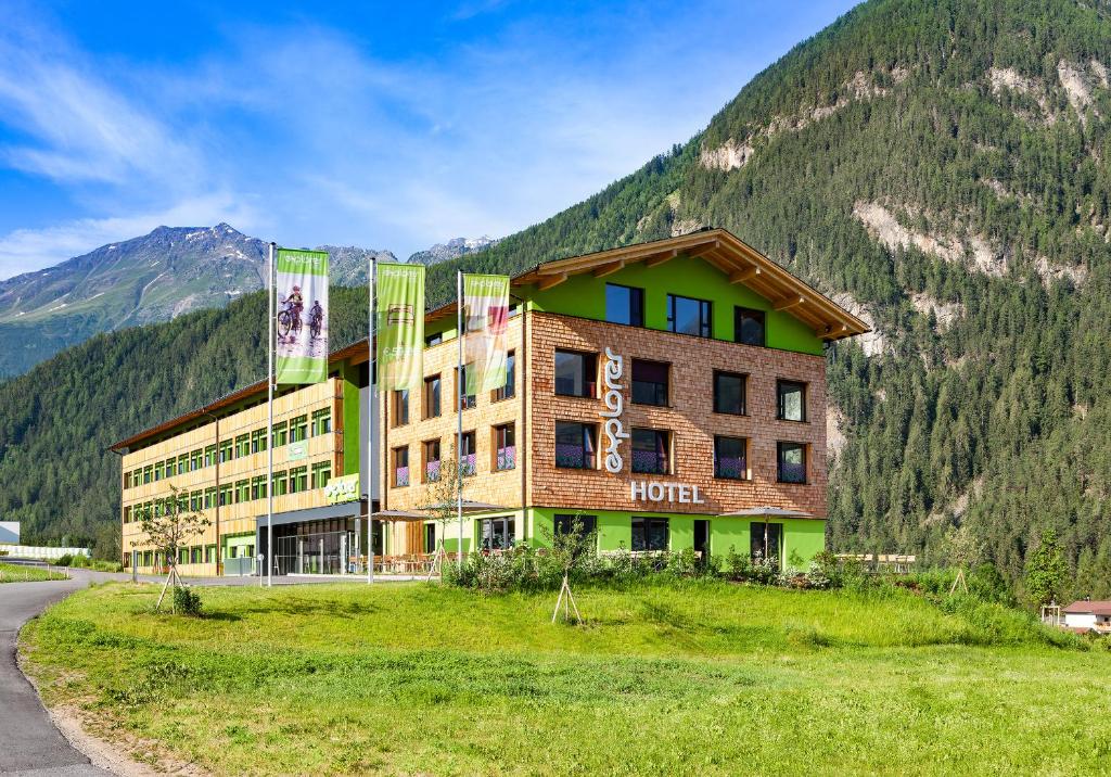 un hotel en una colina con una montaña en Explorer Hotel Ötztal, en Umhausen