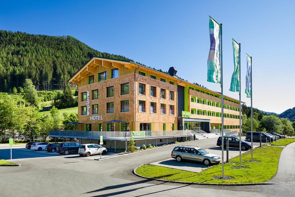 Explorer Hotel Bad Kleinkirchheim في باد كلينكيرشهايم: مبنى كبير به سيارات تقف في موقف للسيارات