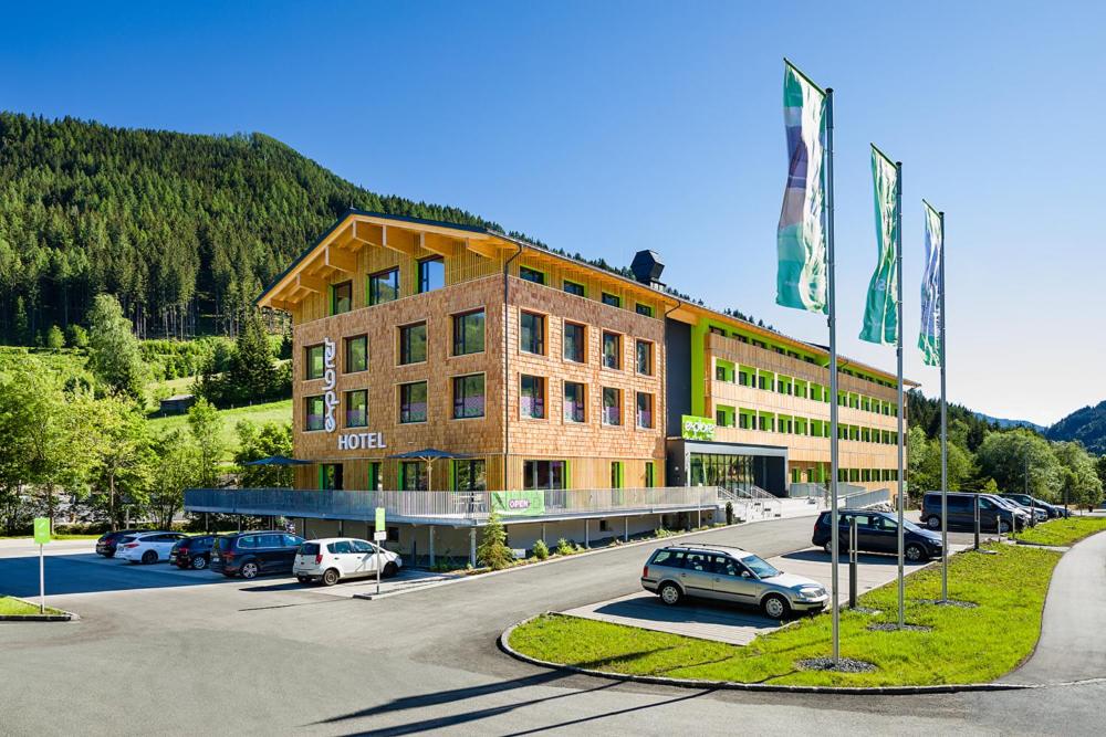 un grand bâtiment avec des voitures garées dans un parking dans l'établissement Explorer Hotel Bad Kleinkirchheim, à Bad Kleinkirchheim