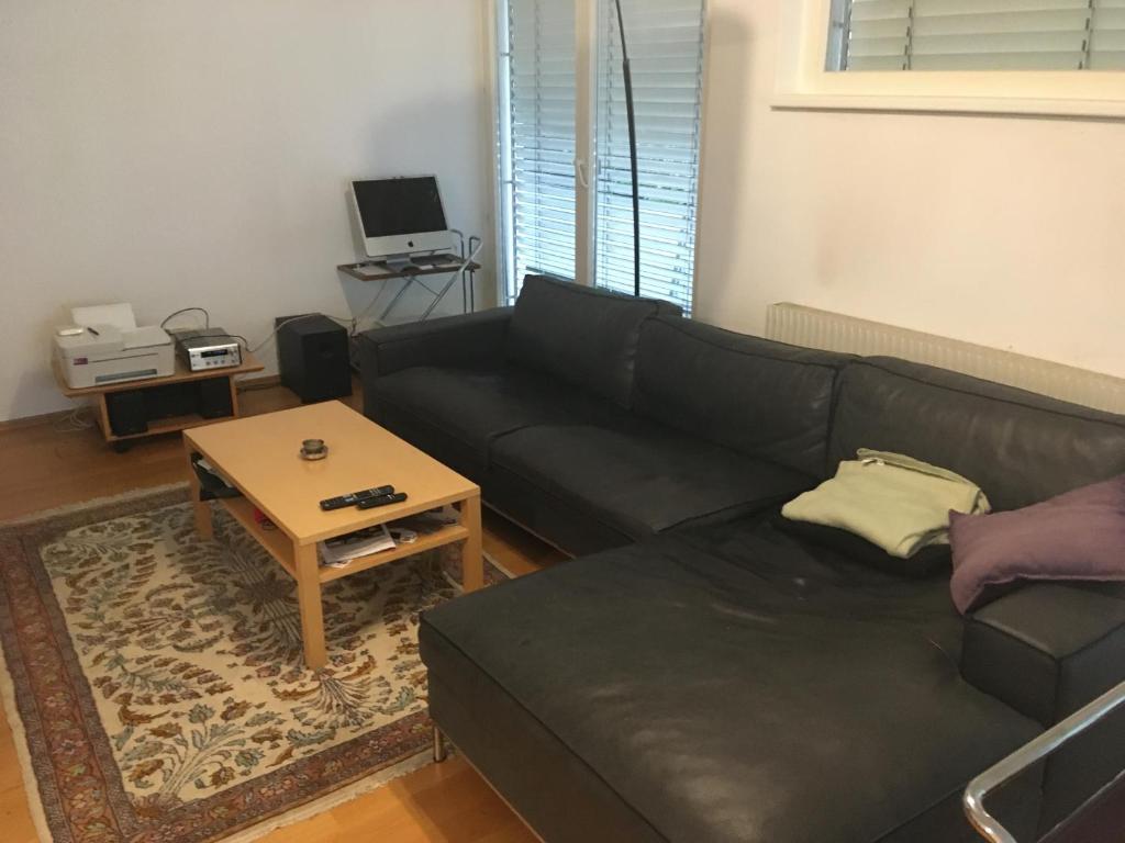 uma sala de estar com um sofá preto e uma mesa em Central em Dornbirn