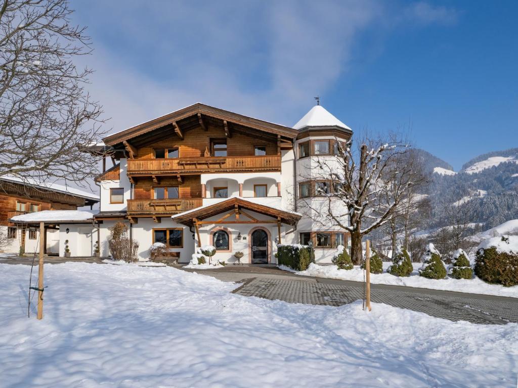 un gran edificio con nieve en el suelo delante en Appartementhaus Fuchs, en Itter