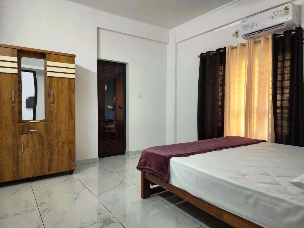 1 dormitorio con 1 cama y puerta de madera en GOPURAM, en Trivandrum