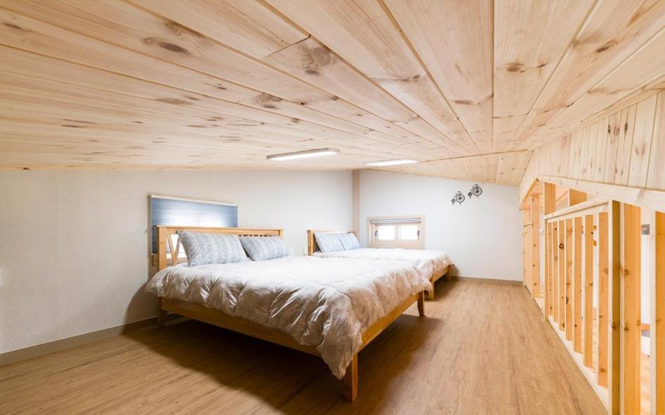 a bedroom with a large bed with a wooden ceiling at Geumdanyoung Pension in Jeju