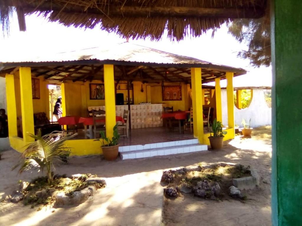 a yellow building with a restaurant with tables and chairs at One Love Beach Bar in Ghana Town