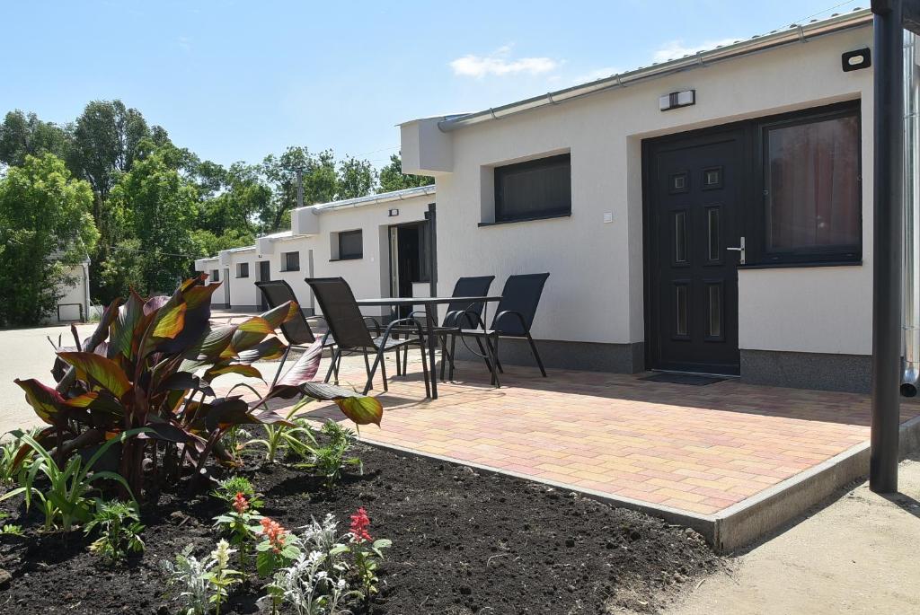 eine Terrasse mit Stühlen und einem Tisch vor einem Haus in der Unterkunft Szentesi Sport- és Üdülőközpont in Szentes