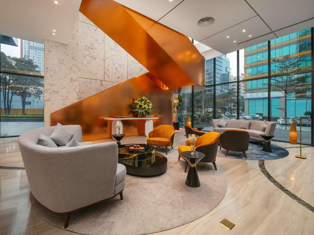 a lobby with couches and chairs in a building at Mövenpick Living West Hanoi in Hanoi