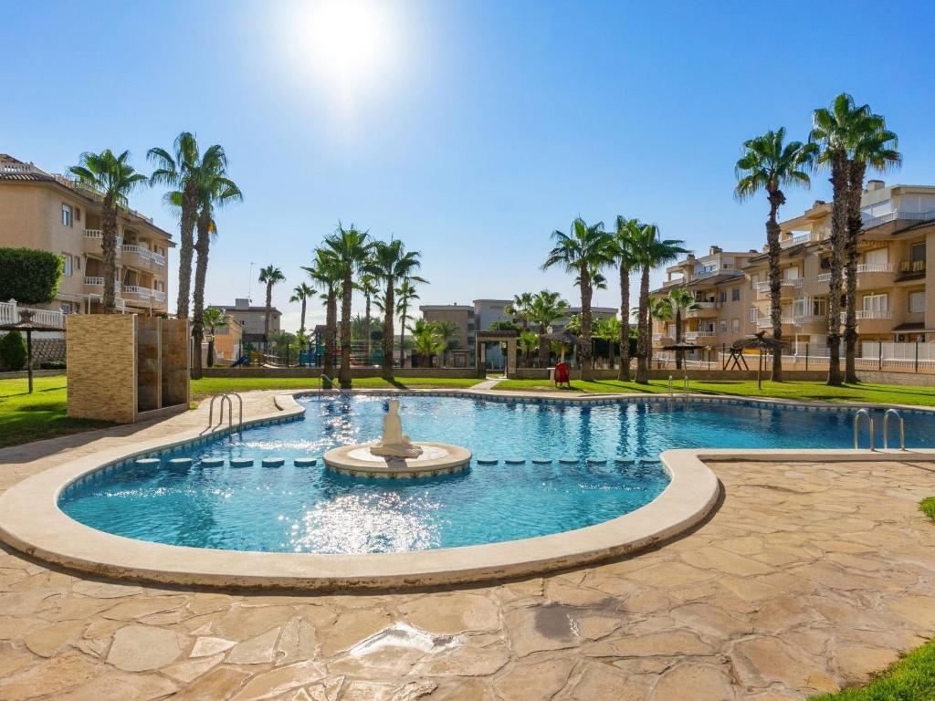 a pool with a fountain in a park with palm trees at Apartment Residencial El Pinar by Interhome in Guardamar del Segura