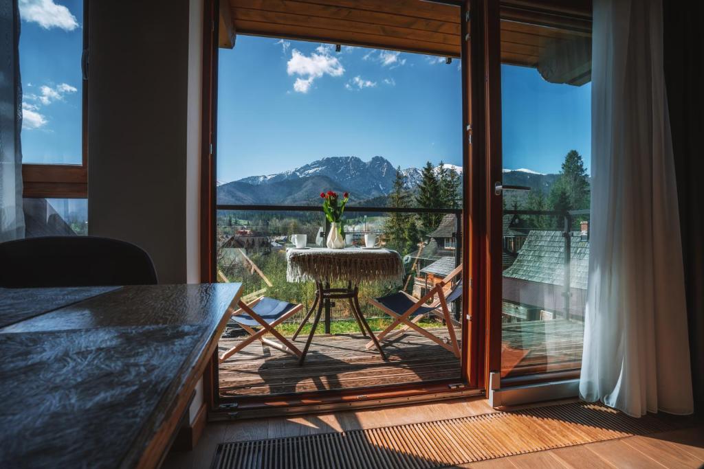 uma varanda com uma mesa e vista para uma montanha em VisitZakopane - Chalet Ski Apartment em Zakopane
