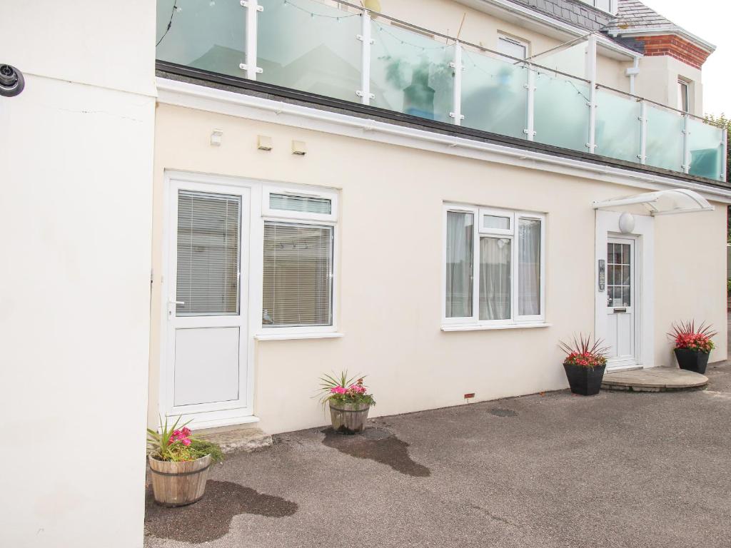 a white house with a balcony on top of it at Sandy Haven in Swanage