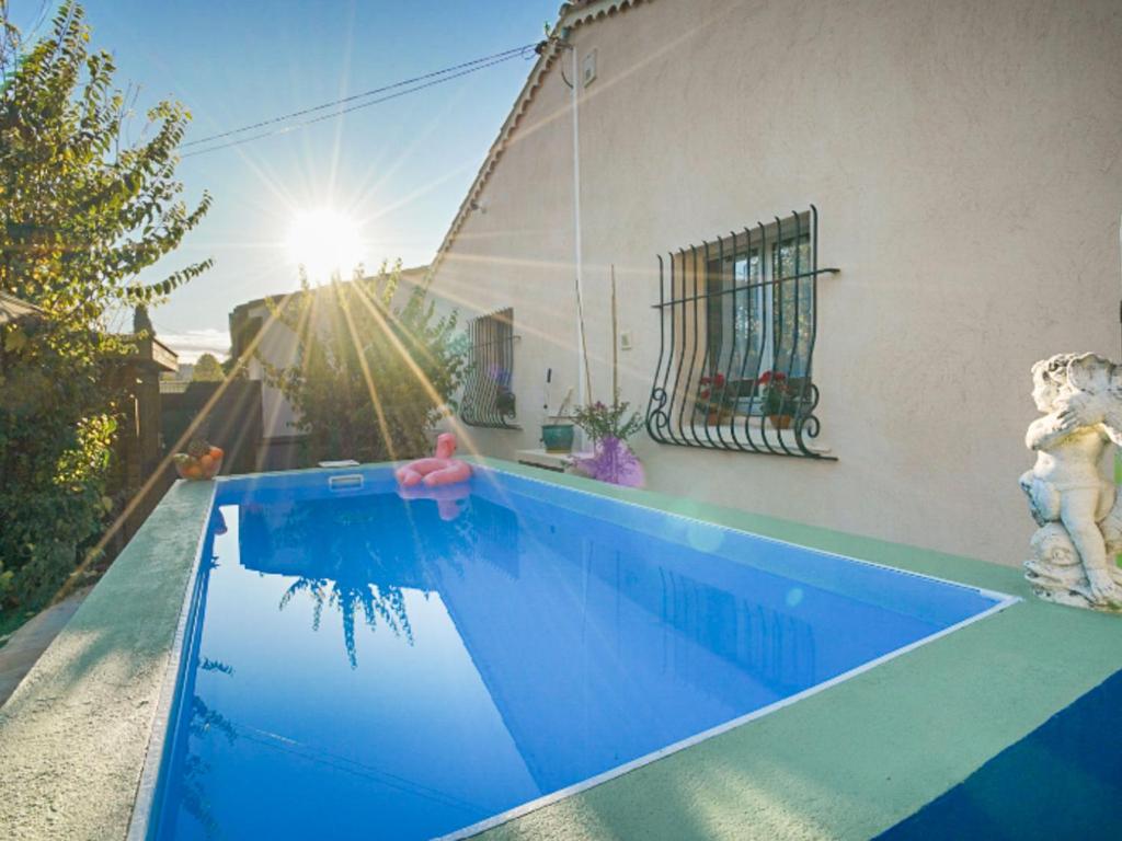 a blue swimming pool with a house and the sun at Villa Liou Miou Souleou by Interhome in Mouans-Sartoux