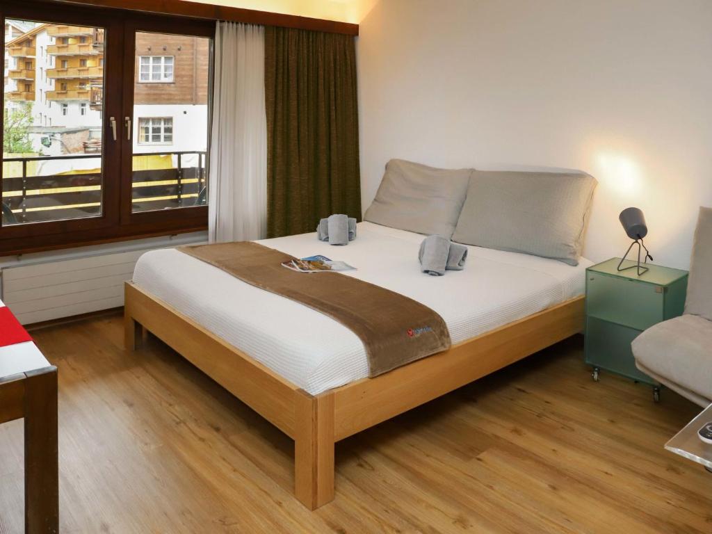 1 dormitorio con 1 cama grande, ventana y silla en Apartment Pasadena-3 by Interhome en Zermatt