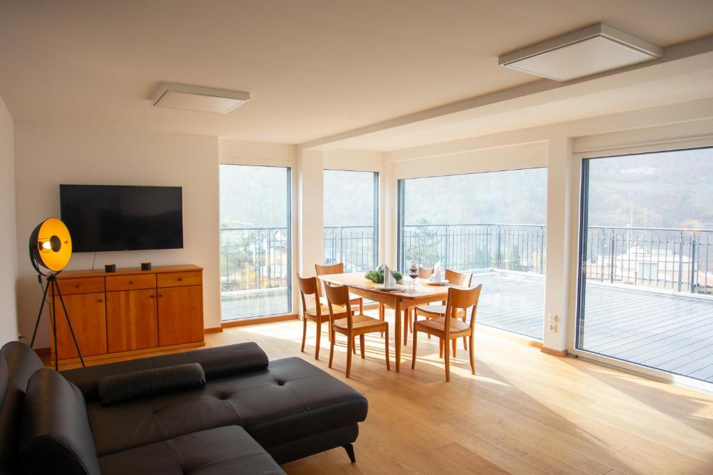 sala de estar con mesa, sillas y TV en Penthouse Visp - mit großer Dachterasse und Panoramablick, en Visp