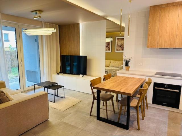 a kitchen and living room with a table and a couch at Apartamenty Sun & Snow Polanka Niemena in Poznań