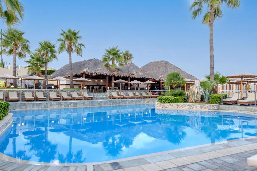 een zwembad in een resort met palmbomen bij Eurohotel Theo Hotel in Agia Marina Nea Kydonias