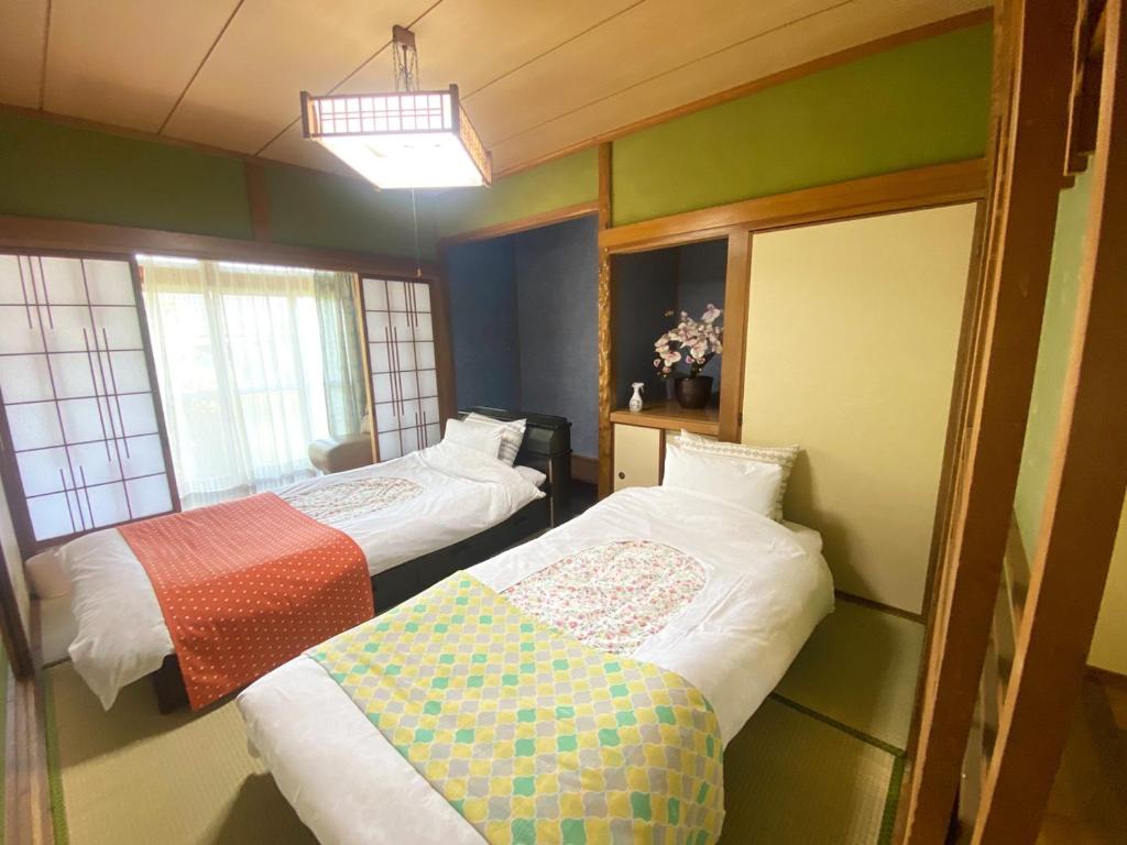two beds in a room with green walls at 鉄道と山の見える家 in Yufu