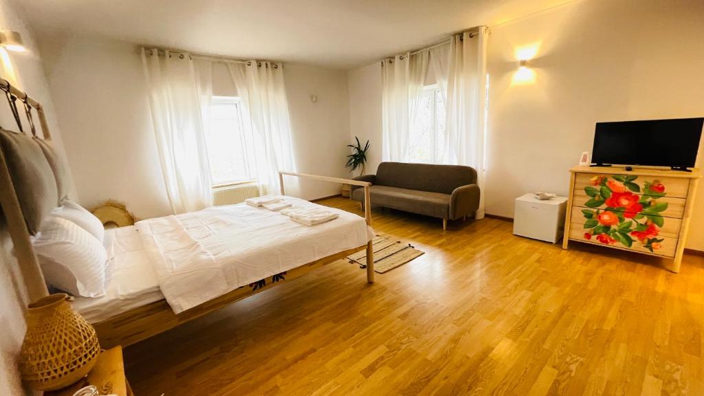 ein Schlafzimmer mit einem Bett, einem Stuhl und einem TV in der Unterkunft BioLocalia House Oltenia in Baloteşti