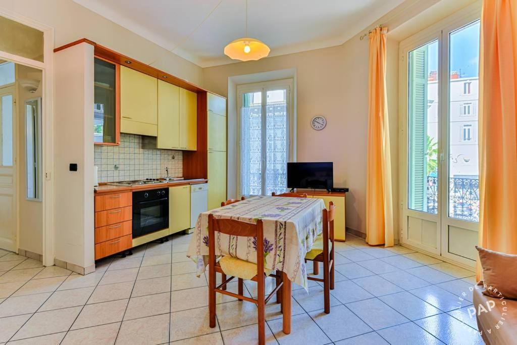 - une cuisine avec une table et des chaises ainsi que quelques fenêtres dans l'établissement Mimosa 1, à Cannes
