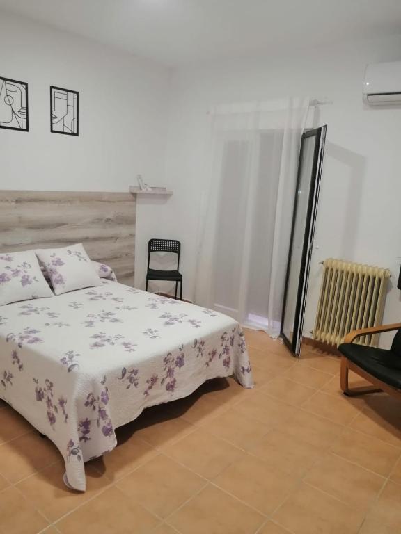 een slaapkamer met een bed en een stoel erin bij La Callejuela Balcón in Villarejo de Salvanés