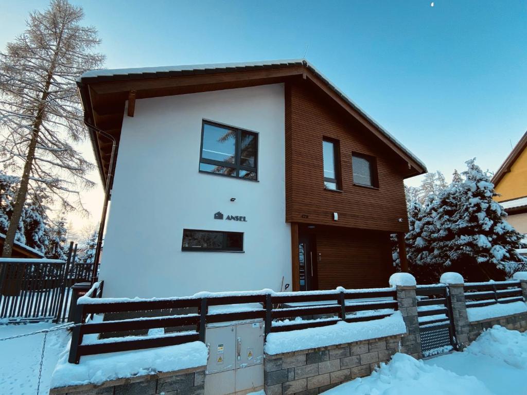 une maison dans la neige avec une clôture dans l'établissement ANSEL Villa, à Stará Lesná