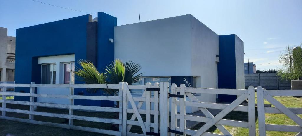 une maison bleue et blanche avec une clôture blanche dans l'établissement Esmeralda casa de Mar, à Camet Norte