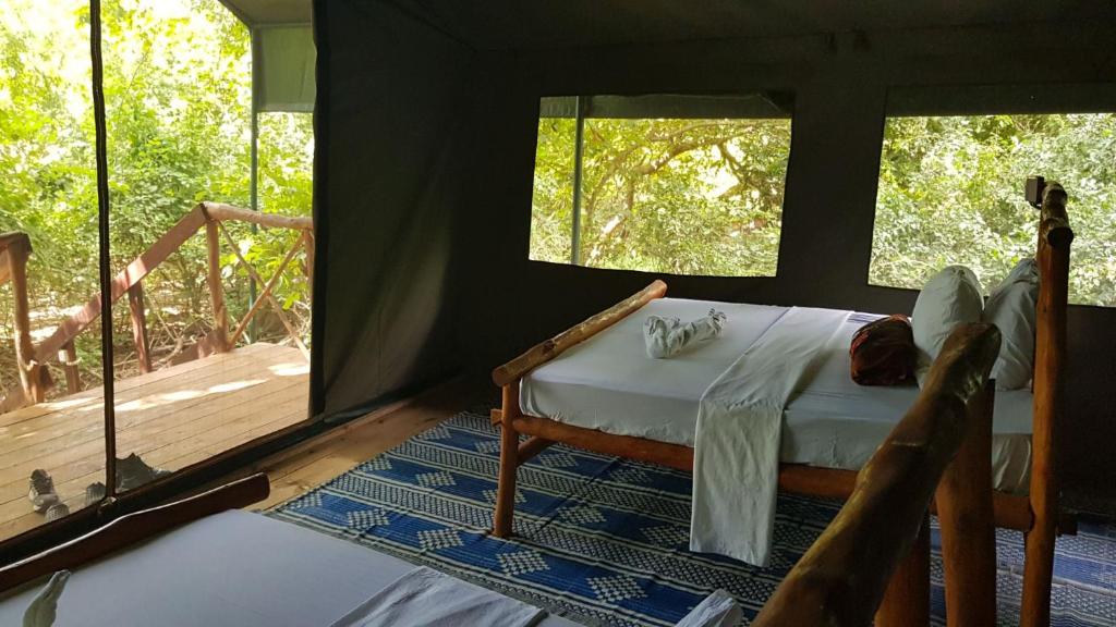 a bedroom with a bed and a deck with windows at Camp Seluu - Safari Pkg in Kwangwazi