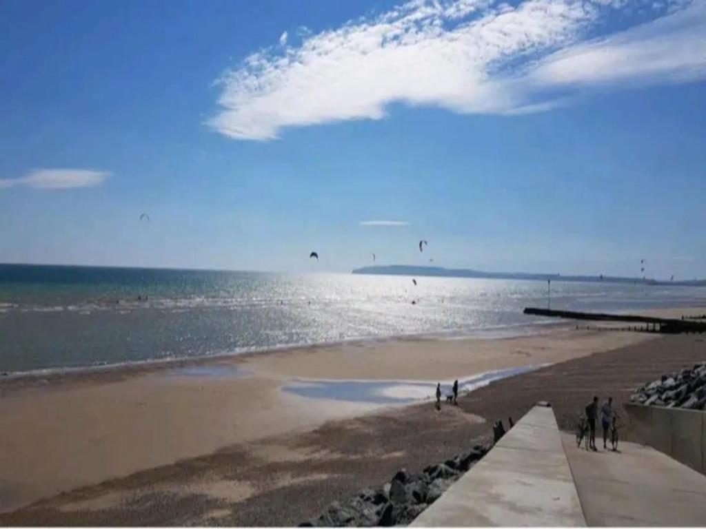 a beach with people walking on the sand and the water at Nollaig Beachside Bliss - Pass the Keys in Rye
