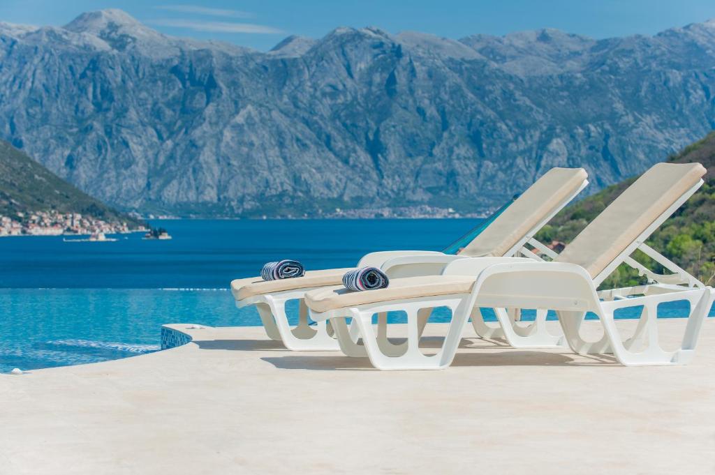 twee witte ligstoelen naast een zwembad bij Lavender Bay Apartment B23 in Kotor