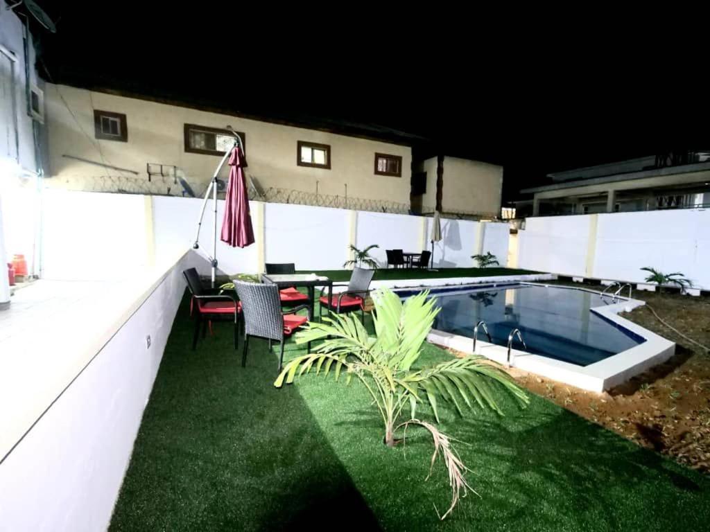 拉各斯的住宿－KAY[POINT APARTMENT，后院设有游泳池、桌子和椅子