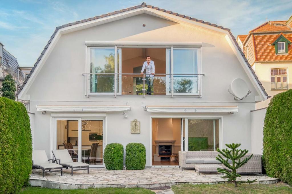 a man standing on the balcony of a house at Villa Vivaldi in Kühlungsborn