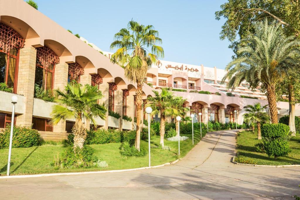 a building with palm trees in front of it at Pyramisa Island Hotel Aswan in Aswan