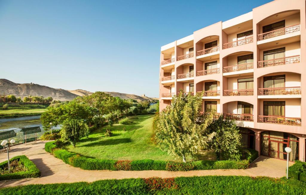 an apartment building with a lawn next to a river at Pyramisa Island Hotel Aswan in Aswan