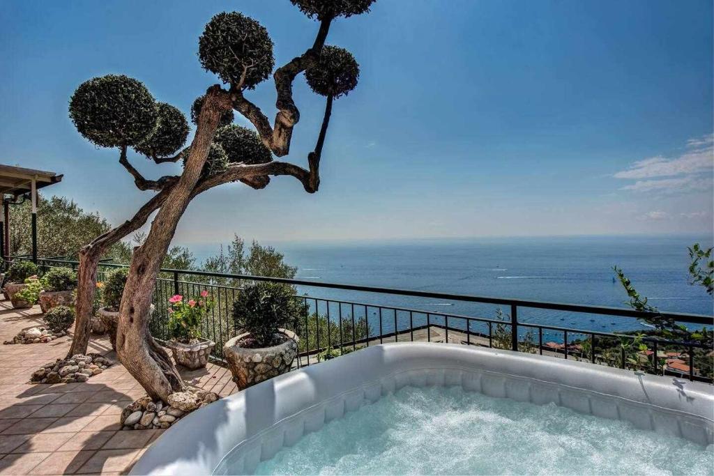 - une piscine avec un arbre et l'océan dans l'établissement Ulivello Country Side Apartment with Sea View, à Massa Lubrense