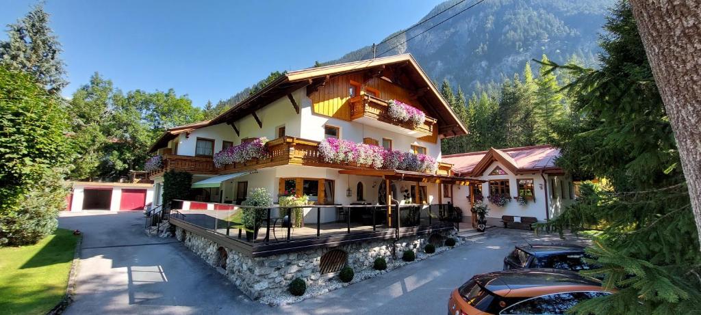 a house in the mountains with flowers on the balcony at Gästehaus Almrausch, Ferienanlage mit Pool in Nassereith