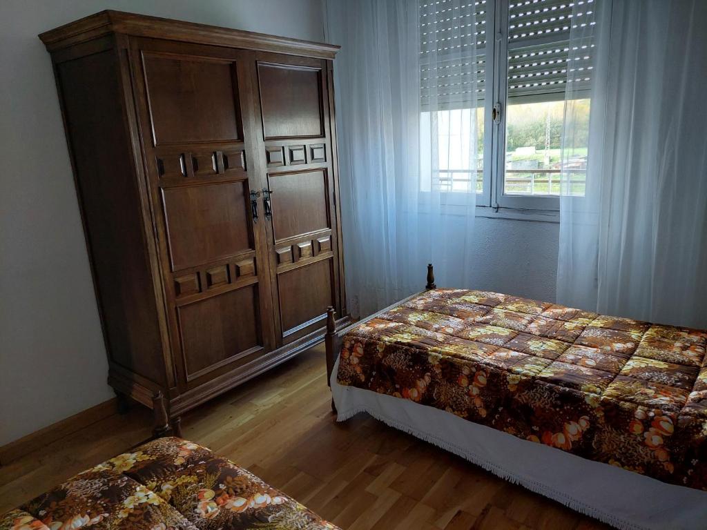 a bedroom with two beds and a large cabinet at Casa MaySa in Cacabelos