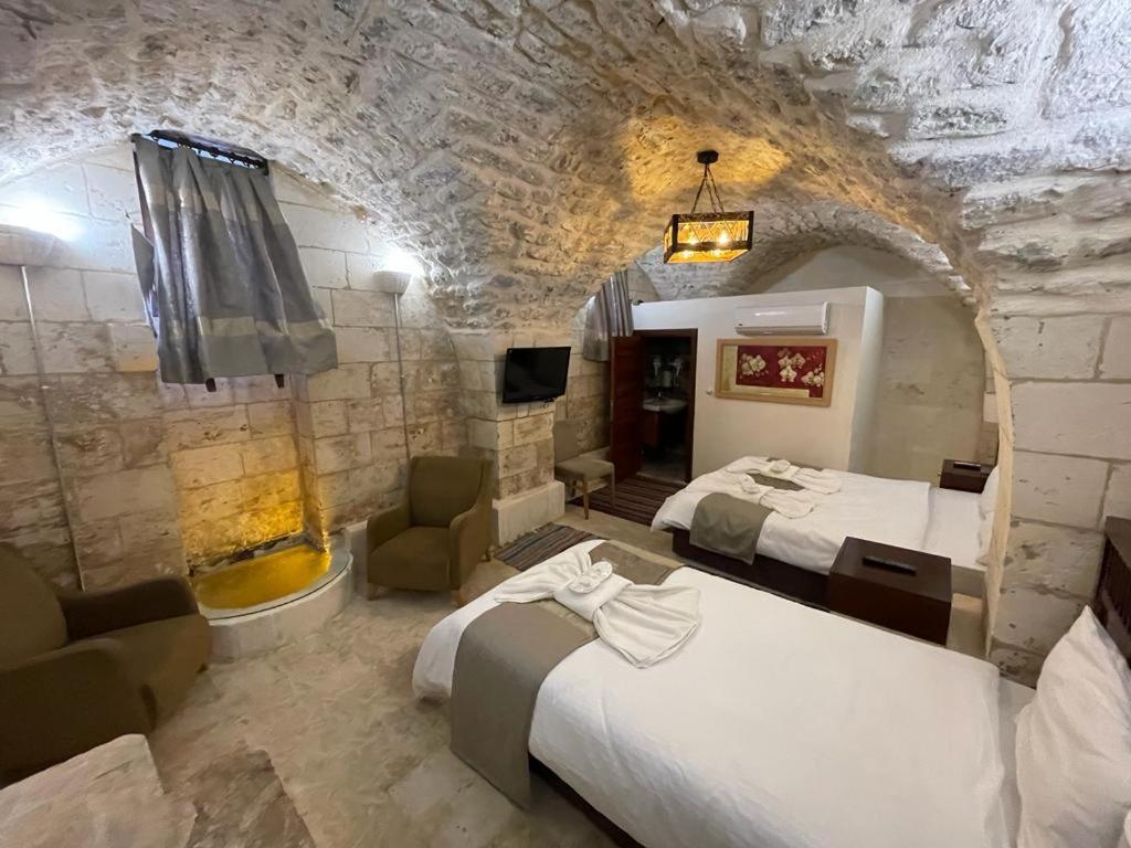 Habitación de hotel con 2 camas y pared de piedra. en Muzepotamia Butik Otel en Sanlıurfa