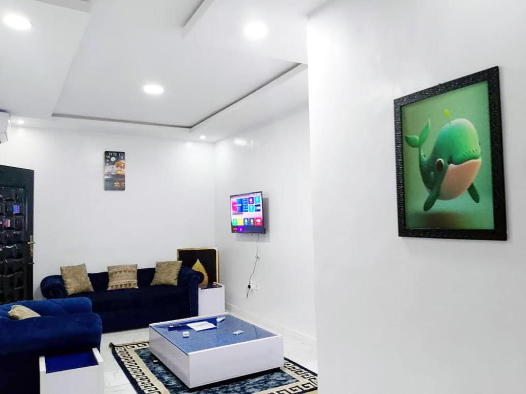 a living room with a blue couch and a tv at JKA 2-Bedroom Luxury Apartments in Lagos