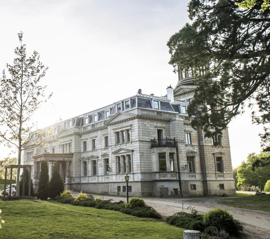 ein großes weißes Gebäude mit einem Baum davor in der Unterkunft Schloss Kaarz mit Park in Kaarz