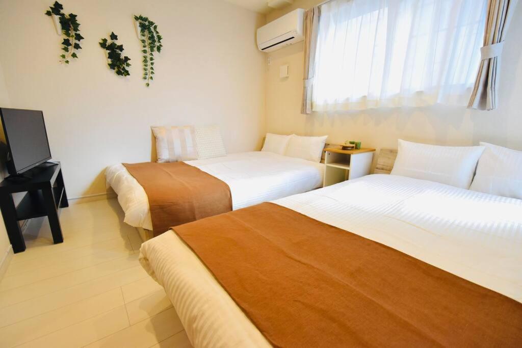 una camera d'albergo con due letti e una televisione di NEW!! 浅草 スカイツリー近く 貸切最大5人 東京観光に最適 無料WiFi a Tokyo