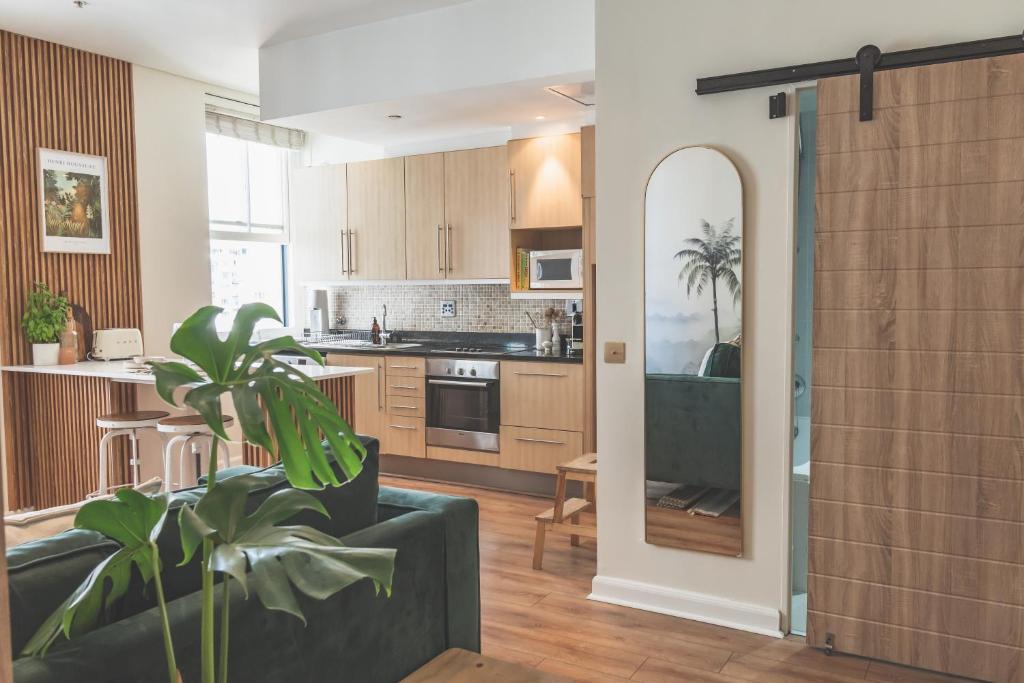 a living room and kitchen with a couch and a plant at Japandi x Jungle Apartment in Cape Town