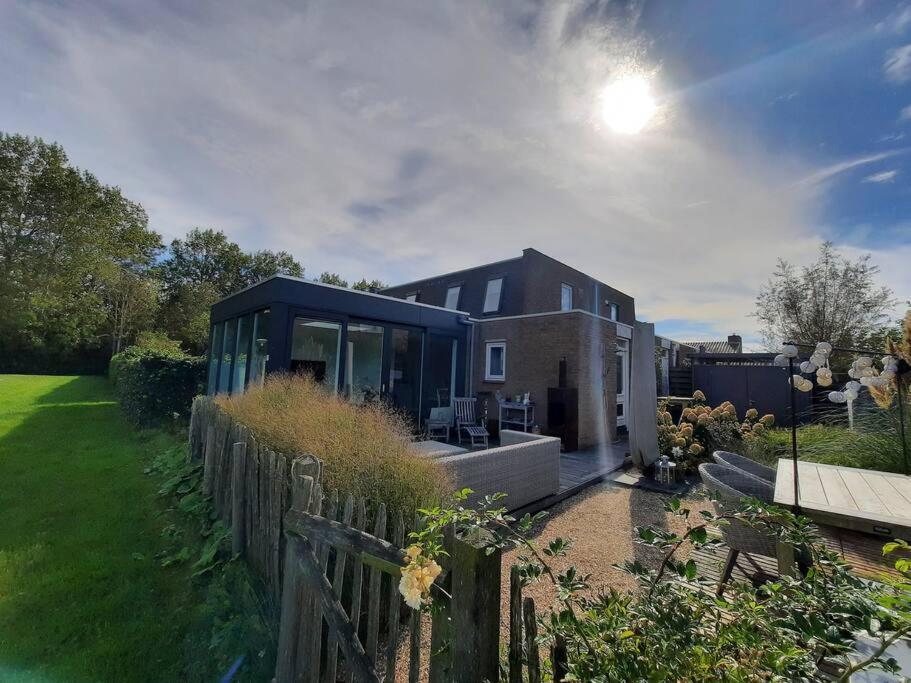 a glass house with a fence in a yard at Lamsoor 9C in Nieuwvliet