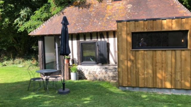 un parasol, une table et une chaise dans la cour dans l'établissement la petite Normande, à Triqueville