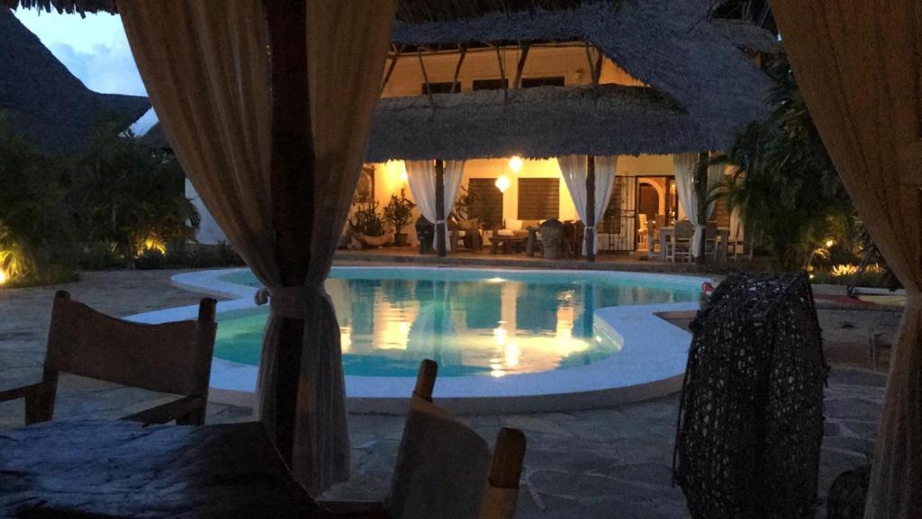 a swimming pool in front of a house at night at White bay pianoB in Watamu