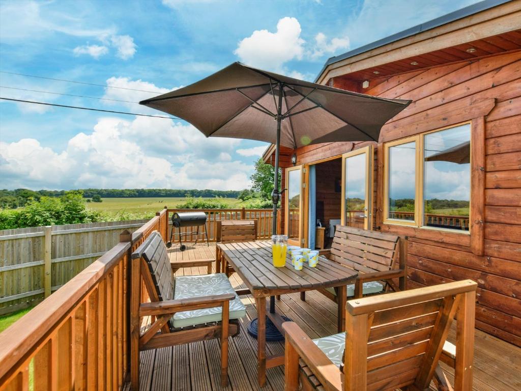 a wooden deck with a table with an umbrella at 3 Bed in Lenham 86252 in Lenham