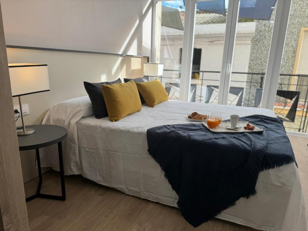 Un dormitorio con una cama con una bandeja de comida. en Apartamentos San Juan Suites, en Badajoz