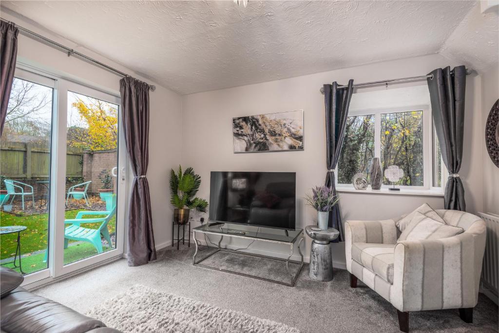 a living room with a couch and a television at WORCESTER Fabulous Cherry Tree Mews self check in dogs welcome by prior arrangement , 2 double bedrooms ,super fast Wi-Fi, with free off road parking for 2 vehicles near Royal Hospital and woodland walks in Worcester