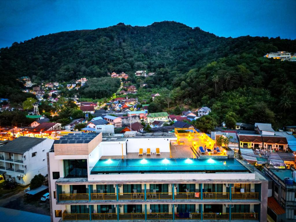 a building with a pool in front of a mountain at Dome Kata Resort in Kata Beach