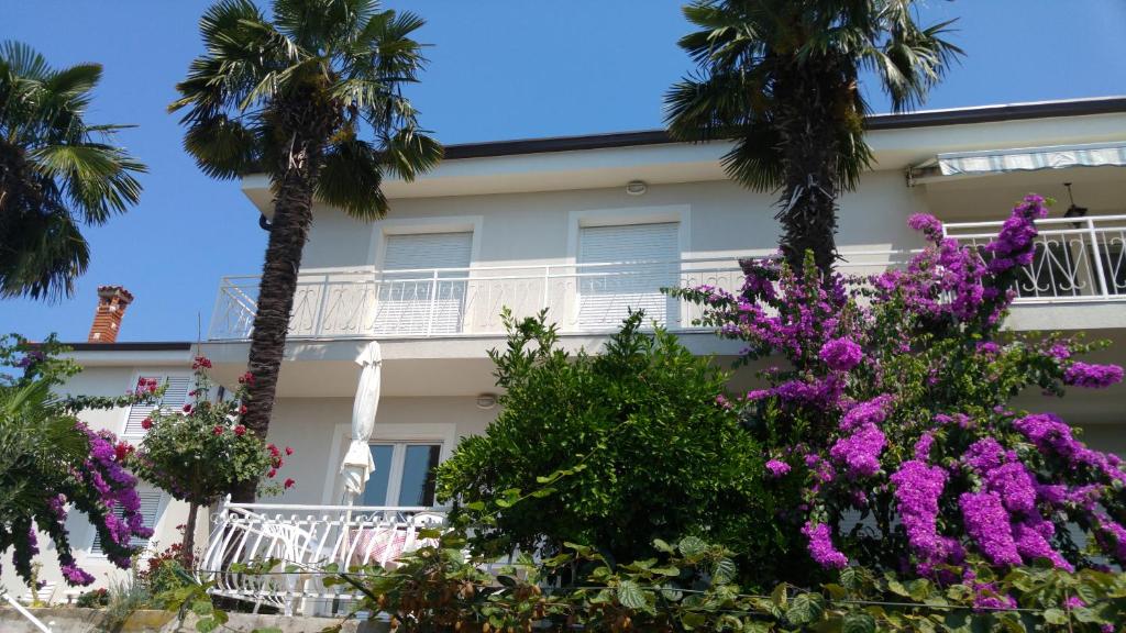 budynek z palmami i fioletowymi kwiatami w obiekcie Apartments Fink w Portorožu