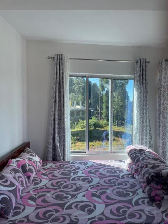 a bedroom with a bed and a large window at Jasmine Homestay Darjeeling in Darjeeling