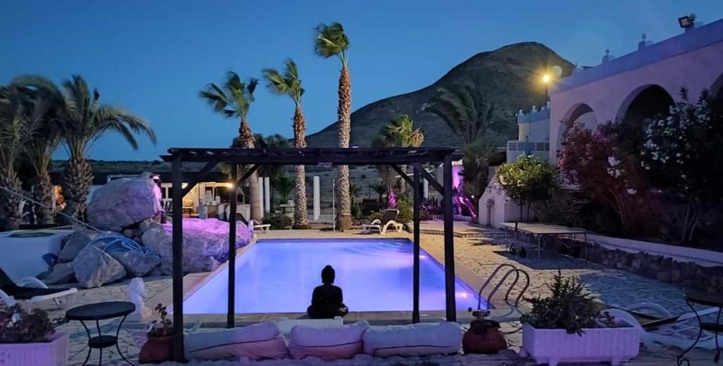 uma pessoa sentada em frente a uma piscina à noite em BlueMar em Almeria