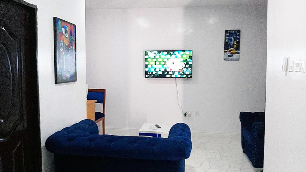 ein Wohnzimmer mit einem blauen Sofa und einem TV in der Unterkunft JKA1-Bedroom Luxury Serviced Apartment in Lagos